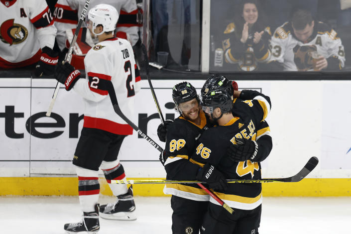 Boston Bruins' David Pastrnak (88) celebrates his goal with teammates David Krejci (46) and Pavel Zacha (18) as Ottawa Senators' Artem Zub (2) skates to the bench during the third period of an NHL hockey game, Monday, Feb. 20, 2023, in Boston. (AP Photo/Michael Dwyer)