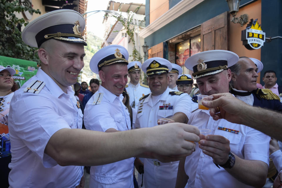 Russian crew members toast with a traditional Venezuelan drink during a welcoming tour by official authorities in La Guaira, Venezuela, after the Almirante Gorshkov frigate and Akademik Pashin oil tanker of the Russian Navy docked there, Tuesday, July 2, 2024. (AP Photo/Ariana Cubillos)