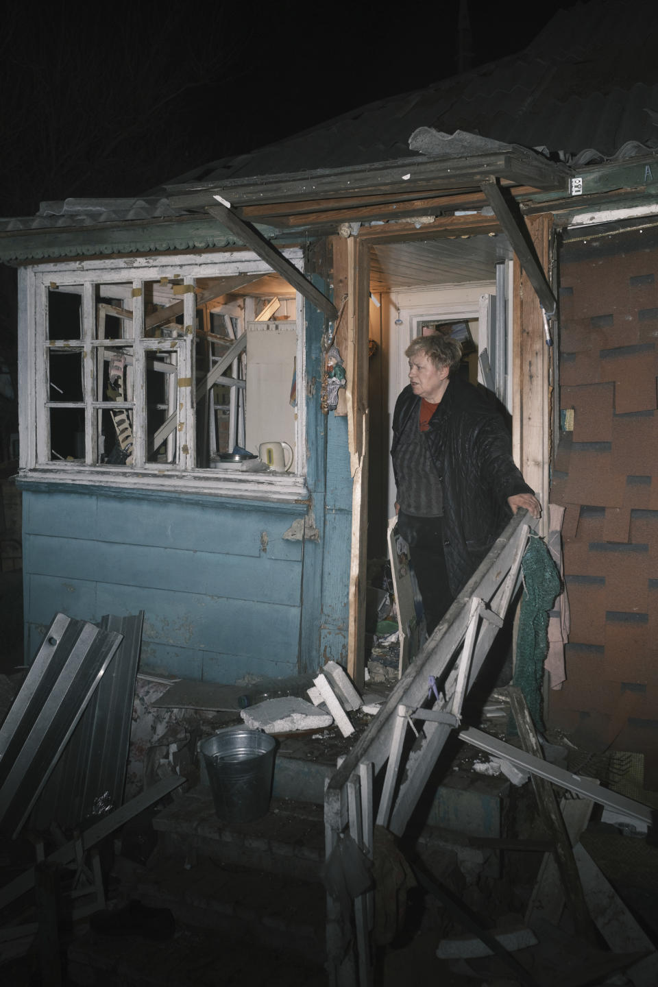 A local woman looks on her house which was damaged after a Russian drone strike on residential neighborhood in Kharkiv, Ukraine, on Thursday, April 4, 2024. (AP Photo/George Ivanchenko)