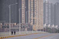 FILE - In this Jan. 28, 2020, file photo, people wearing face masks walk down a deserted street in Wuhan in central China's Hubei Province. (AP Photo/Arek Rataj, File)