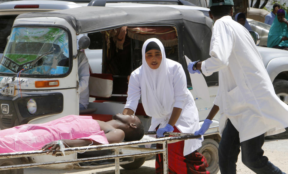 Medical workers help a man who was wounded in a car bomb attack, at Medina hospital, in Mogadishu, Somalia, Monday, July 22, 2019. A Somali police officer says a car bomb in the Somali capital has killed at least 10 people. Capt. Mohamed Hussein said at least 15 others were injured when the car bomb parked near a busy security checkpoint on the city's airport was detonated by remote control. (AP Photo/Farah Abdi Warsameh)