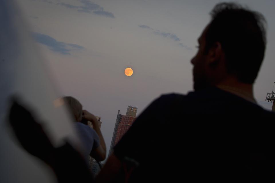 A man is reflected in a car window as he looks at the moon one day ahead of the Supermoon phenomenon from a bridge over 42nd St. in the Manhattan borough of New York July 11, 2014. Occurring when a full moon or new moon coincides with the closest approach the moon makes to the Earth, the Supermoon results in a larger-than-usual appearance of the lunar disk.