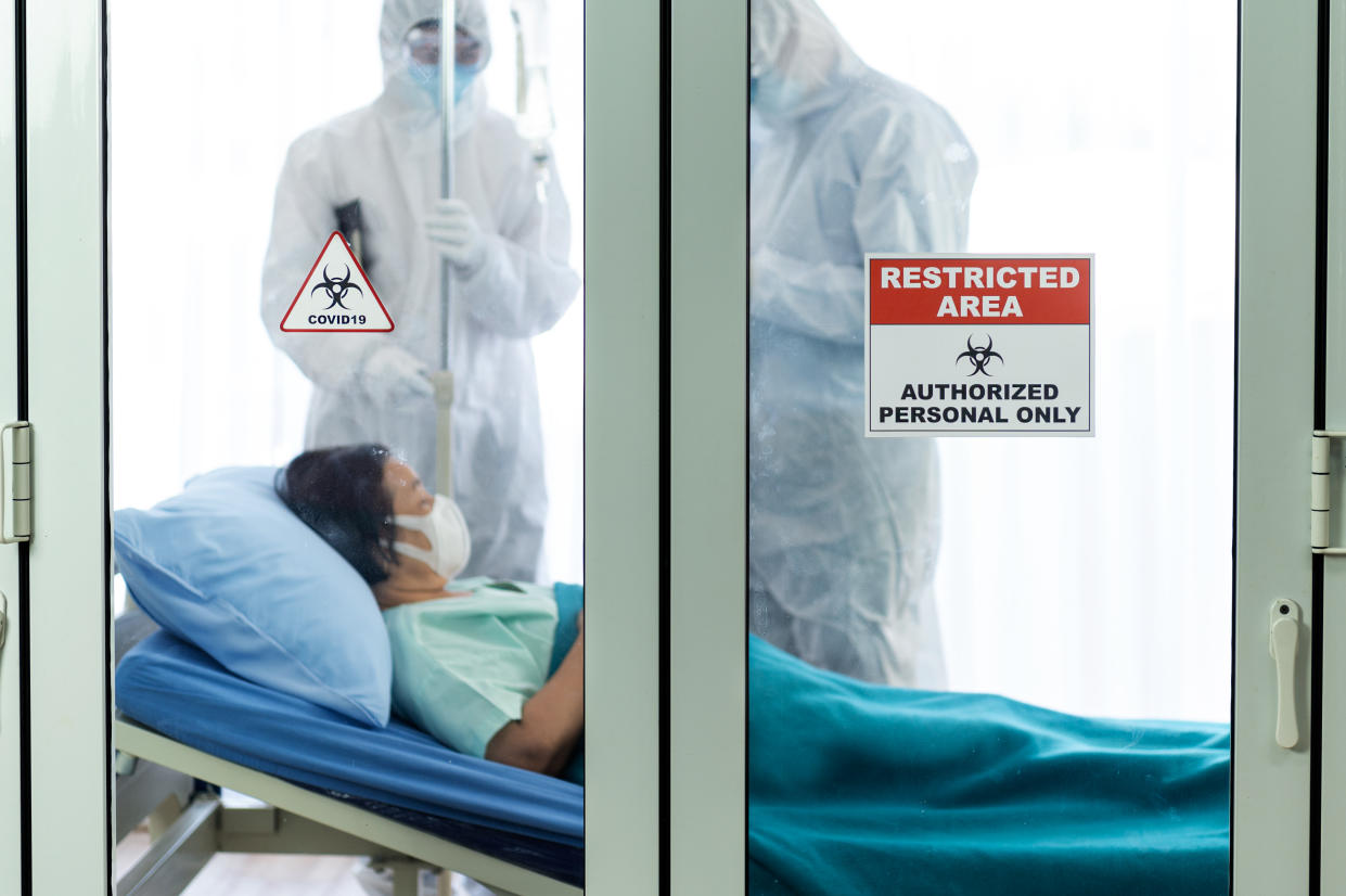 Restricted area and covid-19 signs in front of the clean room with doctors and patient background