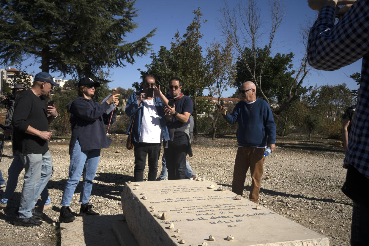 Israeli peace activist gather around the grave of Baruch Goldstein, an Israeli-American religious extremist, in Kiryat Arba, a Jewish settlement on the outskirts of of the embattled West Bank city of Hebron, Friday, Dec. 2, 2022. Israeli peace activists toured the occupied West Bank's largest city Friday in a show of solidarity with Palestinians, amid chants of "shame, shame" from ultra-nationalist hecklers.The encounter in the center of Hebron signaled the widening rift among Israelis over the nature of their society and Israel's open-ended military rule over the Palestinians, now in its 56th year. (AP Photo/Maya Alleruzzo)