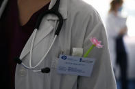 In this photo taken on Thursday, May 7, 2020, a plastic flower is placed on the pocket of the medical student Afroditi Gerodimontaki next to her volunteer card at the Pathological Clinic of Sotiria Hospital in Athens. Greece's main hospital for the treatment of COVID-19 is also the focus of a hands-on training program for dozens of medical students who volunteered to relieve hard-pressed doctors from their simpler duties while gaining a close peek at the front lines of a struggle unmatched in modern medical history. (AP Photo/Thanassis Stavrakis)