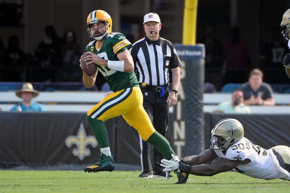 Green Bay Packers quarterback Aaron Rodgers, left, scrambles as he is pressured by New Orleans Saints linebacker Tanoh Kpassagnon during the first half of an NFL football game, Sunday, Sept. 12, 2021, in Jacksonville, Fla. (AP Photo/Phelan M. Ebenhack)