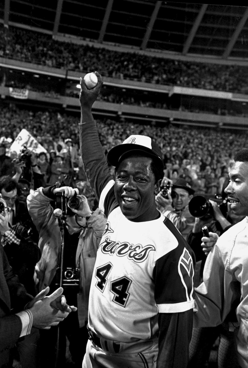 FILE - Hank Aaron holds aloft the ball he hit for his 715th career home run, against the Los Angeles Dodgers in Atlanta, Ga., Monday night, April 8, 1974. Just in time for the 50-year anniversary of Hank Aaron's record 715th home run, Charlie Russo is making available video he shot of the homer.(AP Photo/Bob Daugherty, File)