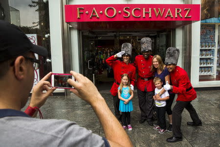 Tourists pose with costumed employees outside of the toy store FAO Schwarz on the last day that the store will be open in New York, July 15, 2015. REUTERS/Lucas Jackson