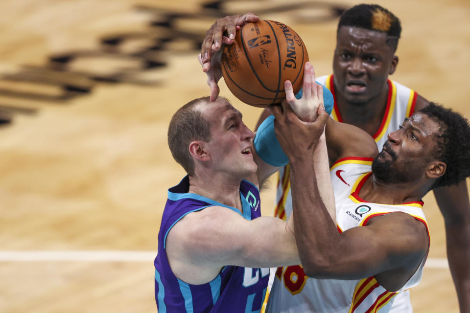 Charlotte Hornets center Cody Zeller, left, and Atlanta Hawks forward Solomon Hill, right, the battle for the ball during the third quarter of an NBA basketball game in Charlotte, N.C., Sunday, April 11, 2021. (AP Photo/Nell Redmond)