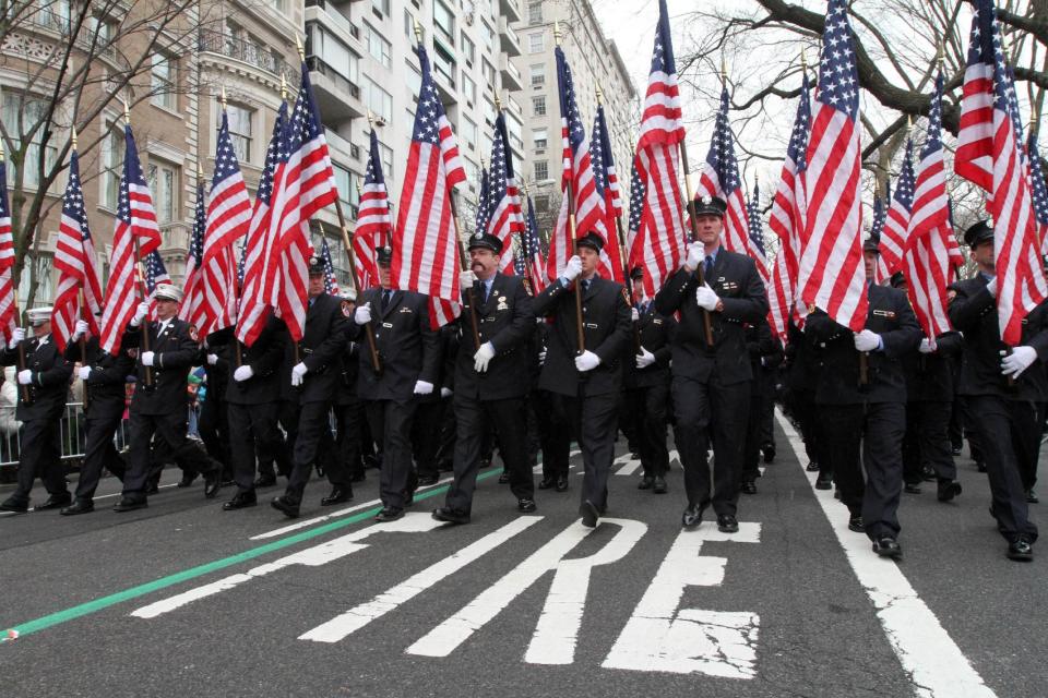 FILE - In this Saturday, March 16, 2013 file photo, holding flags in memory of the 343 firefighters who lost their lives in the Sept. 11 attacks, members of the New York City Fire Department walk up New York's Fifth Avenue as they take part in the St. Patrick's Day Parade. Since the 1990s, the event's ban on gay signs and banners has spurred protests and litigation and led to the creation of an alternative, gay-friendly St. Patrick's Day parade in Queens. (AP Photo/Tina Fineberg)