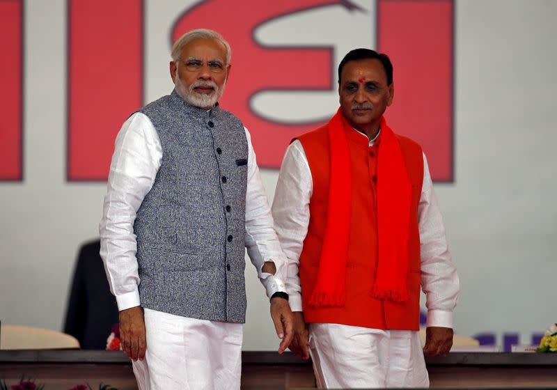 FILE PHOTO: Vijay Rupani walks with India's PM Modi after taking his oath as the chief minister of the western state of Gujarat during a swearing-in ceremony at Gandhinagar