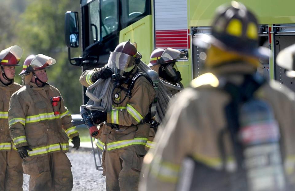 Firefighters from the University Park Airport pull hoses from the truck as they complete a building fire training session at the Centre County Public Safety Training Center on Wednesday, Oct. 11, 2023.