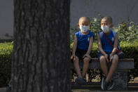 Children wearing masks to curb the spread of the coronavirus sit on a bench in Beijing, China on Monday, July 13, 2020. China reported only a handful of new cases of the virus, all of them brought from outside the country, as domestic community infections fall to near zero. (AP Photo/Ng Han Guan)