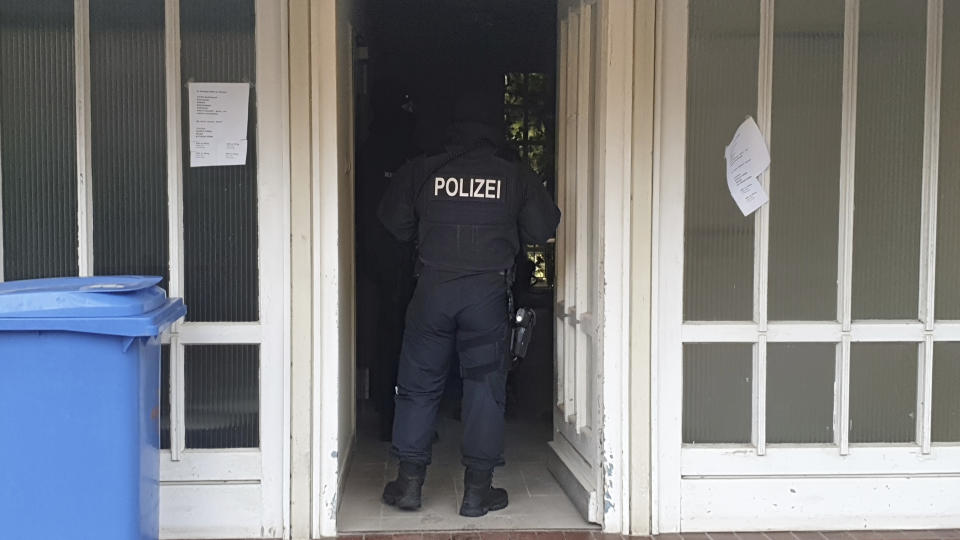 CORRECTS NAME OF LOCATION A police officer stand in an entrance of an apartment building during a raid in the village Meldorf, Germany, Jan. 30, 2019. German authorities arrested three suspected Islamic extremist Iraqi men in the norther German costal region, on allegations they were planning a bombing. (Karsten Schroeder/dpa via AP)