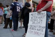 Fans carrying a sign (R) and wearing a New England Patriots quarterback Tom Brady jersey (L) wait in line to hear Brady speak at Salem State University in Salem, Massachusetts, United States May 7, 2015. REUTERS/Brian Snyder