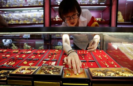 A sales assistant takes out gold ornaments for a customer at Caibai Jewelry store in Beijing