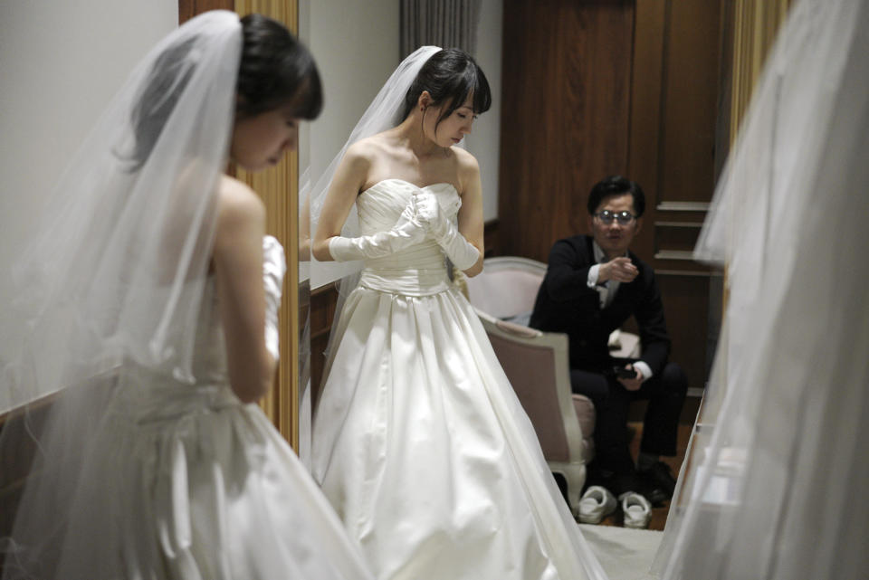 In this April 11, 2019, photo, Kenzo Watanabe, right, looks at his fiancee Chiharu Yanagihara trying on a wedding dress at a Japanese wedding company in Tokyo. Japan is getting ready for its biggest celebration in years with the advent of the Reiwa era of soon-to-be emperor Naruhito. That means big opportunities for businesses hoping consumers will splash out on long holidays and memorabilia. (AP Photo/Eugene Hoshiko)