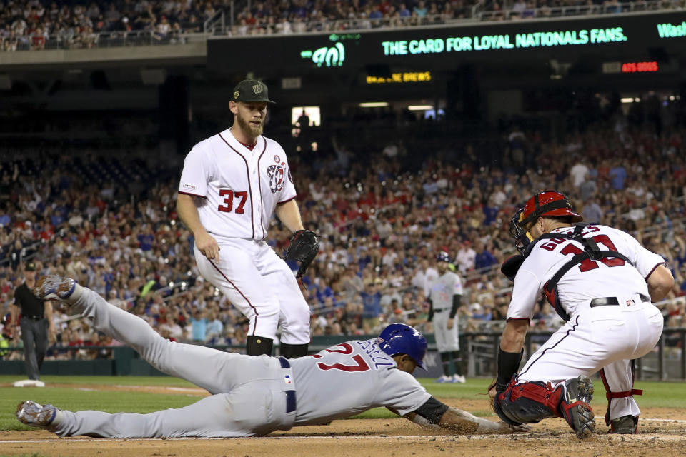 Washington Nationals starting pitcher Stephen Strasburg (37) watches as catcher Yan Gomes (10) tags out Chicago Cubs' Addison Russell (27) who tried to score on a passed ball during the fifth inning of a baseball game Saturday, May 18, 2019, in Washington. (AP Photo/Andrew Harnik)