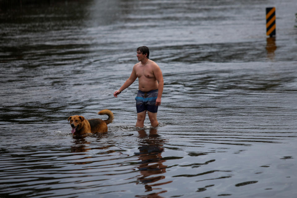 A man and his dog walk along a flooded street after the passage of tropical storm Florence in New Bern, North Carolina, U.S., September 16, 2018.&nbsp;