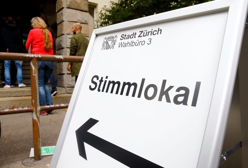 People stand in front of a polling station for the Swiss federal elections in Zurich