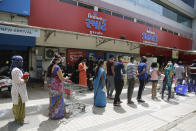 Indians stands in queue outside a store to purchase essential items during lockdown as a precautionary measure against COVID-19 in Ahmedabad, India, Tuesday, March 24, 2020. For most people, the new coronavirus causes only mild or moderate symptoms. For some it can cause more severe illness. (AP Photo/Ajit Solanki)