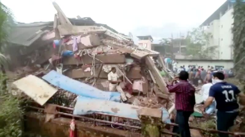 People are seen near the scene of a five-story building that collapsed in Raigad in the western state of Maharashtra
