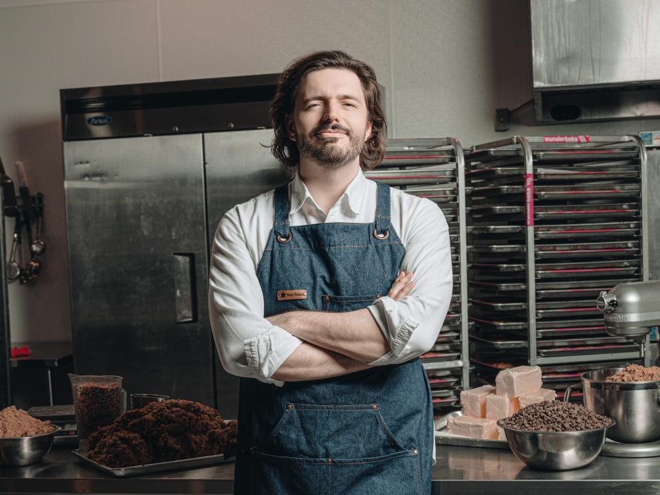 Hans Shrei stands with his arms crossed in an industrial kitchen