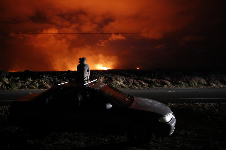 Brittany Kimball watches as lava erupts from from a fissure near Pahoa, Hawaii, Saturday, May 19, 2018. AP Photo/Jae C. Hong