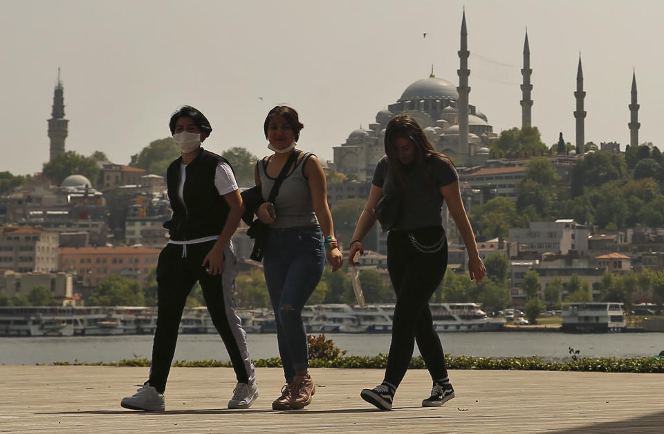 Turkish girls walk in Istanbul, backdropped by the Suleymaniye Mosque, Friday, May 15, 2020. Teenagers were able to leave their homes for the first time in 42 days on Friday, as their turn came for a few hours of respite from Turkey's coronavirus lockdowns. Turkey has subjected people aged 65 and over and those younger than 20, to a curfew for the past several weeks. (AP Photo/Emrah Gurel)