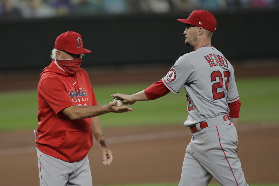 Los Angeles Angels starting pitcher Andrew Heaney, right, is pulled by manager Joe Maddon during the sixth inning of the team's baseball game against the Seattle Mariners, Tuesday, Aug. 4, 2020, in Seattle. (AP Photo/Ted S. Warren)