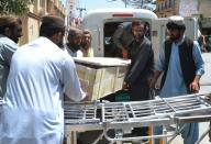 Pakistani security officials and hospital staff move a dead body into a morgue in Quetta on May 22, 2016, following the drone strike in Ahmad Wal, Balochistan