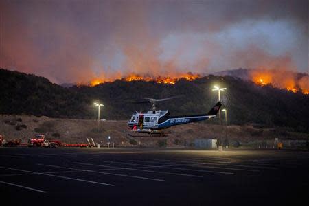 A helicopter is seen as firefighters battle a blaze in San Marcos, California May 14, 2014. REUTERS/Sam Hodgson