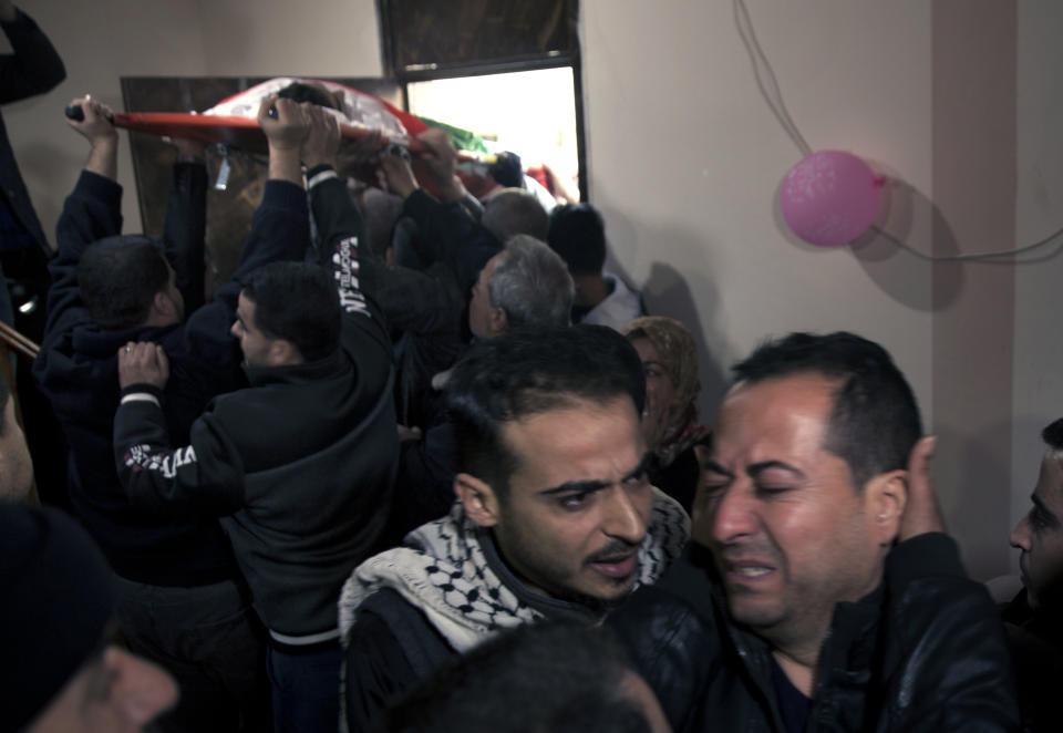 Relatives of 16 year-old Palestinian Mohammed Jahjouh, who was shot and killed by Israeli troops during a protest at the Gaza Strip's border with Israel, mourn as others carry his body into the family home during his funeral in Gaza City, Saturday, Dec. 22, 2018. (AP Photo/Khalil Hamra)