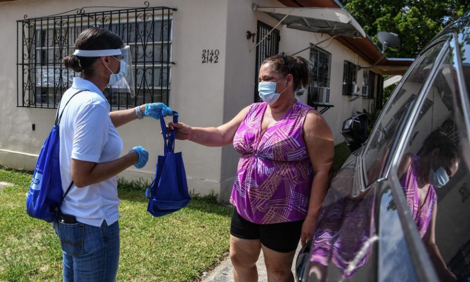 Catherimarty Burgos, a member of Miami-Dade County “surge teams”, distributes bags with masks, sanitizers, and gloves in Miami.