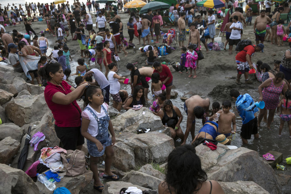 In this Feb. 23, 2020 photo, people put on their street clothes after spending a day at Agua Dulce beach in Lima, Peru. Most of the beachgoers arrive and return home on public transportation, a 12 mile (20 kilometers) trip south of the city center. (AP Photo/Rodrigo Abd)