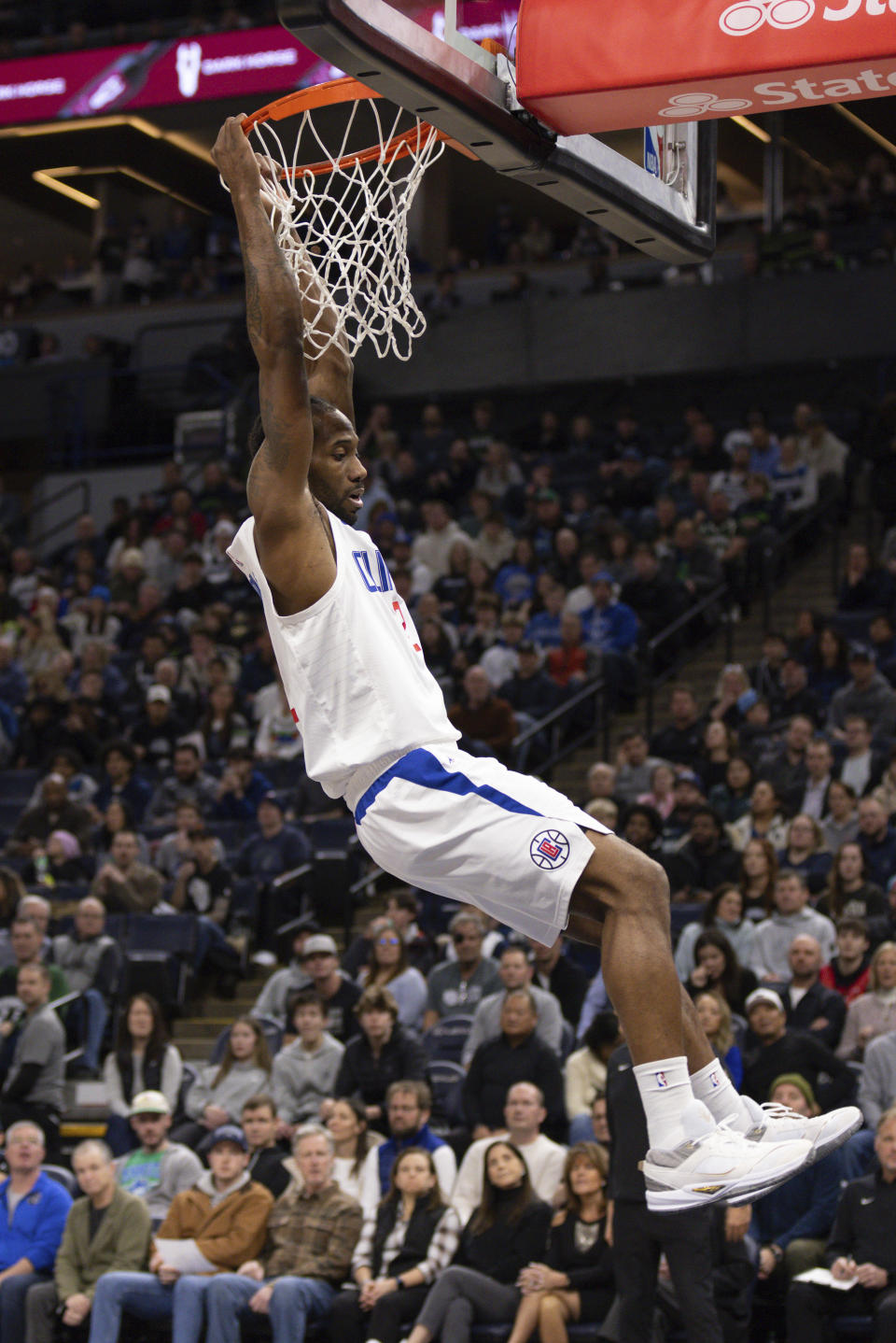 Los Angeles Clippers forward Kawhi Leonard hangs on the rim after a dunk during the first half of an NBA basketball game against the Minnesota Timberwolves, Sunday, Jan. 14, 2024, in Minneapolis, Minn. (AP Photo/Bailey Hillesheim)