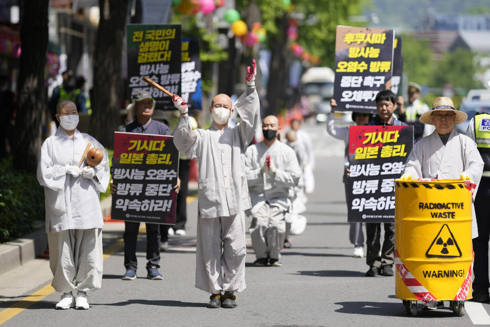 South Korean Buddhist monks, Buddhists and members of civic groups bow which they prostrate themselves, on a road in a march as they move toward to Japanese Embassy during a rally demanding the stop of Japanese government's decision to release treated radioactive water from the Fukushima, in Seoul, South Korea, Monday, May 8, 2023. The part of letters read "Japanese Prime Minister Fumio Kishida" and "Promise to stop the release treated radioactive water." (AP Photo/Lee Jin-man)