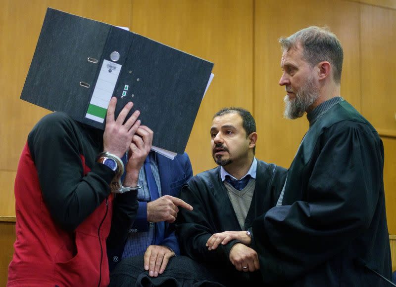 Iraqi defendant covers his face as he arrives for his verdict in a courtroom in Frankfurt