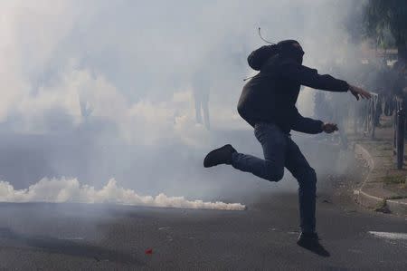 A masked youth runs through a cloud of tear gas during clashes with gendarmes and police during a demonstration against the French labour law proposal in Paris, France, as part of a nationwide labor reform protests and strikes, April 28, 2016. REUTERS/Philippe Wojazer