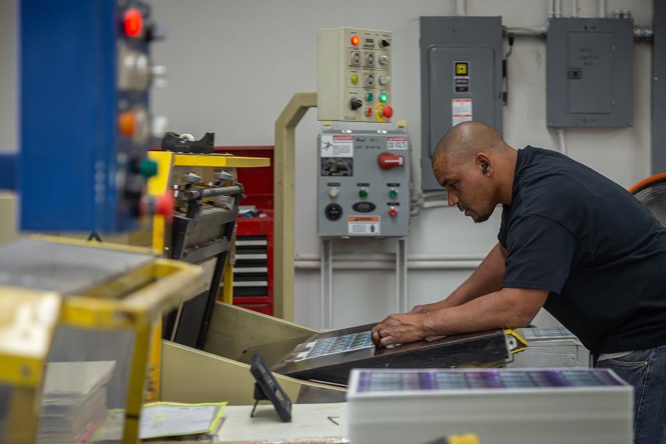 Angel Penalver cuts sheets of laminated cards on a die cutting press at k12 Print's production facility in Riviera Beach, Fla., on April 24, 2024.