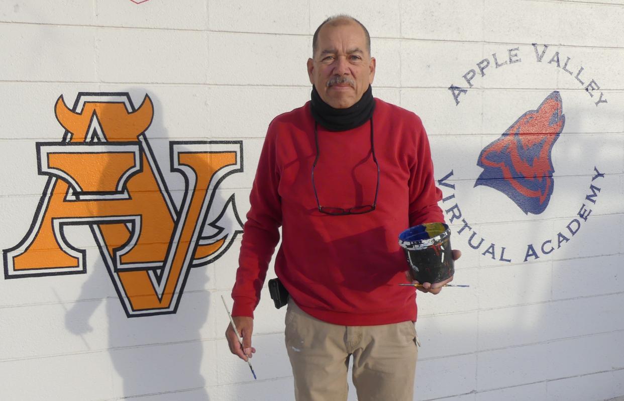 Business owner Miguel Gonzalez continues painting by hand, over a dozen school logos for the Apple Valley Unified School District.