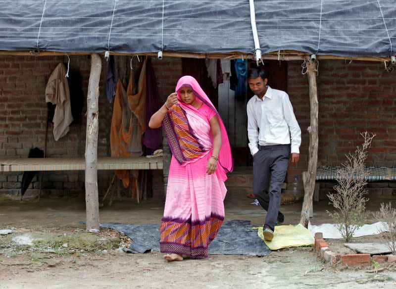 Ashish Kumar walks with his mother Bittu Devi outside their house in Dutta Nagar