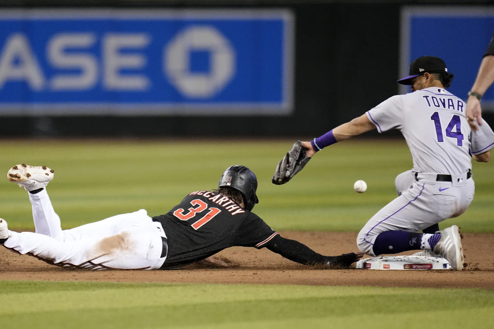Arizona Diamondbacks' Jake McCarthy (31) dives safely back to second base as Colorado Rockies shortstop Ezequiel Tovar (14) is unable to make a catch on a pickoff throwing error by Rockies pitcher Peter Lambert during the fourth inning of a baseball game Wednesday, May 31, 2023, in Phoenix. Diamondbacks' McCarthy was able to advance to third base on the play. (AP Photo/Ross D. Franklin)