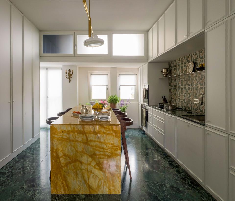 In the Milan kitchen of Karla Otto CEO Alexander Werz, Sicilian tile accents white cabinetry in the kitchen; the stools, light fixture, and bespoke marble table are all by Giorgia Longoni.