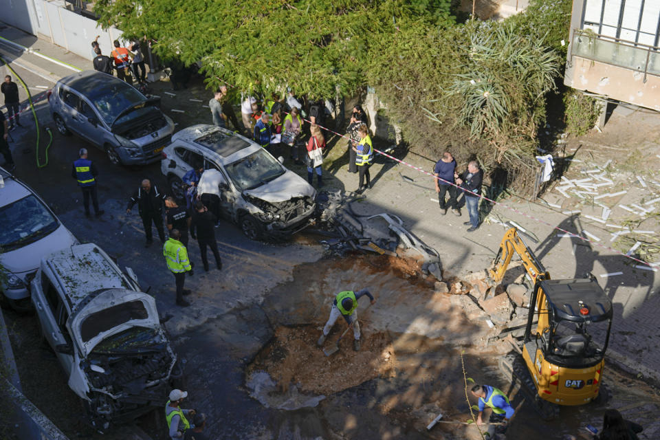 Israeli security forces inspect a site hit by a rocket fired from the Gaza Strip, in Holon, central Israel on Monday, Dec. 11, 2023. (AP Photo/Ariel Schalit)