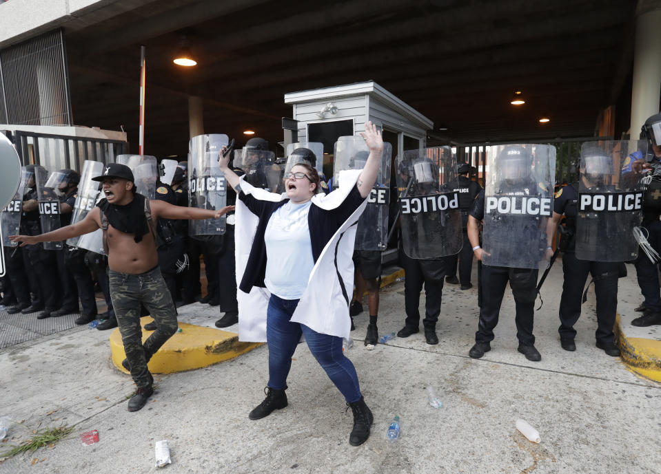 A pair of protesters attempt to stop others from throwing rocks and water bottles at police during a demonstration next to the city of Miami Police Department, Saturday, May 30, 2020, downtown in Miami. Protests were held throughout the country over the death of George Floyd, a black man who died after being restrained by Minneapolis police officers on May 25. (AP Photo/Wilfredo Lee)