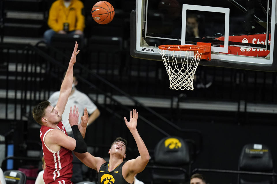 Wisconsin forward Micah Potter, left, shoots over Iowa center Luka Garza during the first half of an NCAA college basketball game, Sunday, March 7, 2021, in Iowa City, Iowa. (AP Photo/Charlie Neibergall)