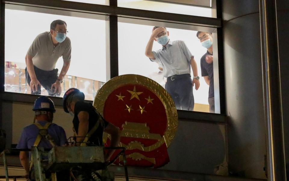 Workers place a national emblem outside the Metropark Hotel Causeway Bay Hong Kong - Reuters