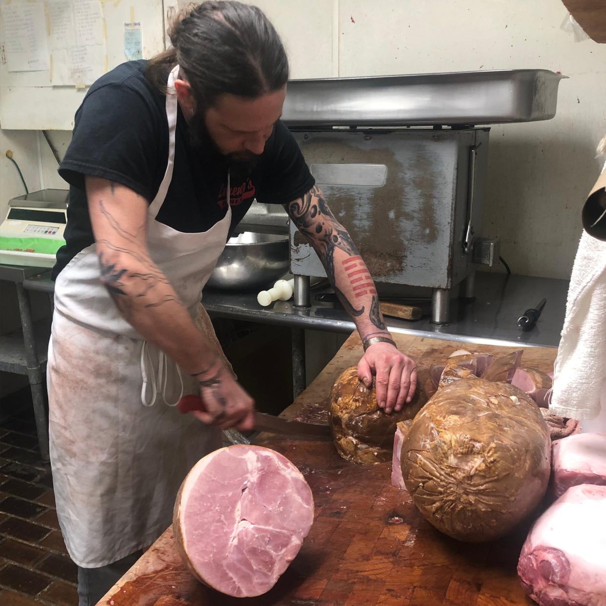 Jeremy Young, an employee at Rose's Hillcrest Market in Alliance, butchers a ham, preparing it for resale. The butcher shop at 1475 W. State St. will permanently close Tuesday.