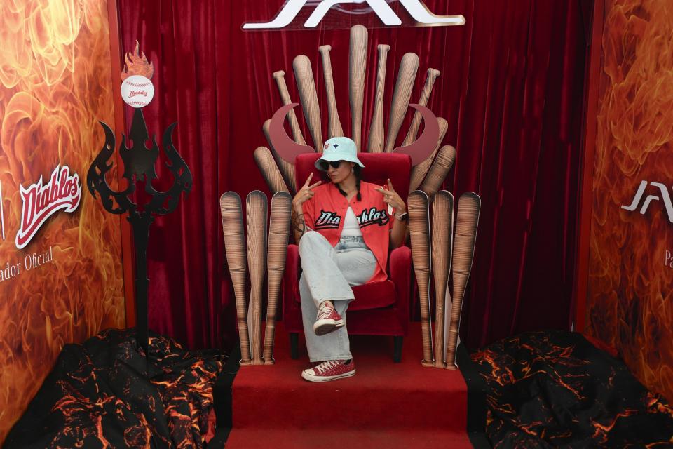 A fan strikes a pose as she sits in a baseball throne prior to a Mexican league game between the Diablos Rojo and the Tigres of Quintana Roo, at the Alfredo Harp Helu Stadium in Mexico City, April 16, 2024. (AP Photo/Fernando Llano)